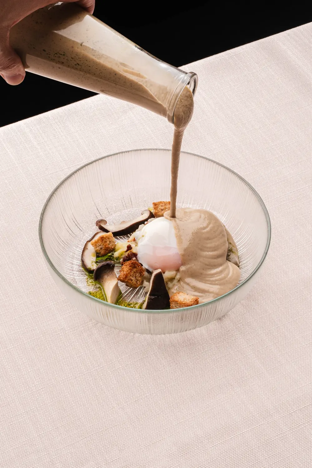 Chef serving a mushroom soup with poached egg at a private home